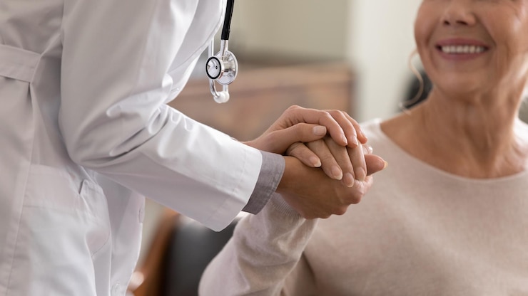 Foto médico dando esperança imagem em close de jovem médica inclinando-se para a paciente idosa sorridente segurando sua mão nas palmas mulher zeladora em casaco branco apoiando e encorajando uma pessoa idosa