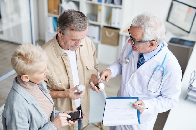 Médico dando pílulas para casal sênior