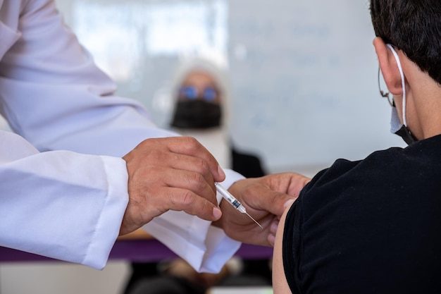 Médico dando la vacuna a los estudiantes en el aula