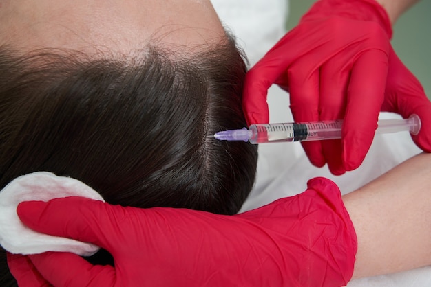 Médico de beleza faz injeções de beleza para rejuvenescimento de ácido hialurônico na cabeça de uma bela jovem