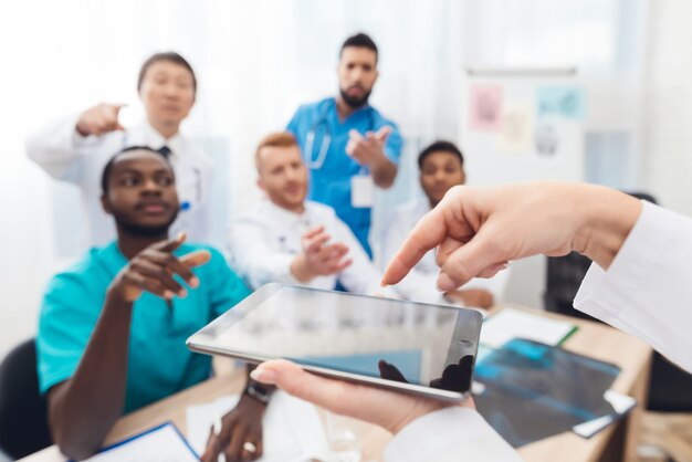 Foto médico de cabeça feminina mostra colegas algo sobre o tablet.