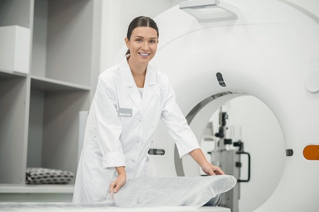 Médico de cabelos compridos, preparando o scanner de ressonância magnética para o trabalho