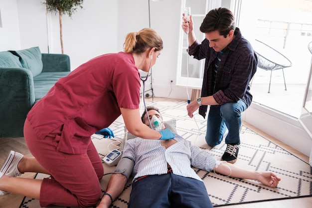 Foto médico de emergência atendendo uma emergência em uma casa e recebe ajuda de um colega de quarto conceito de emergências médicas cuidados de saúde