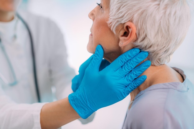 Foto médico de endocrinologia examinando uma mulher idosa com sintomas de doença da glândula tireóide