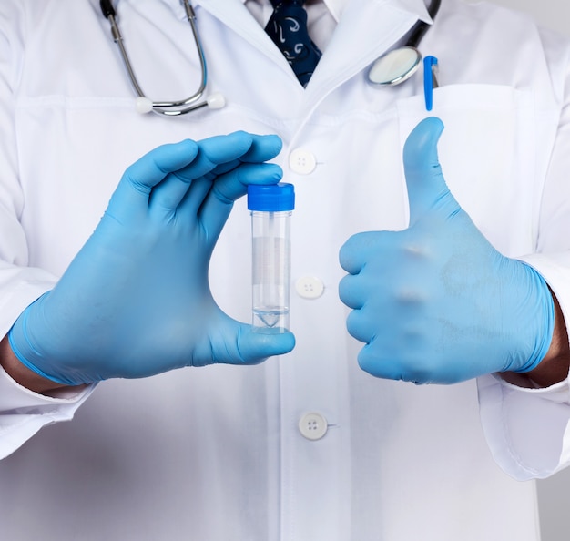 Médico de jaleco branco e luvas azuis de látex estéreis segura um frasco de plástico para análise de fezes