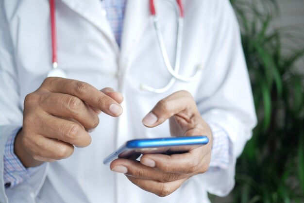 Médico de jaleco branco usando um smartphone