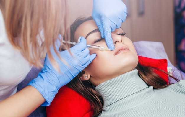 Médico de luvas dando injeções nos lábios da mulher