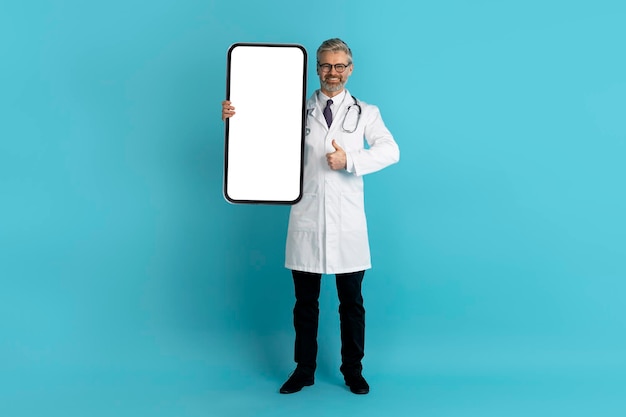 Médico de meia-idade amigável mostrando um bom aplicativo de telemedicina no smartphone