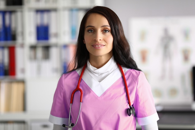 Médico de mulher bonita em uniforme fica no escritório