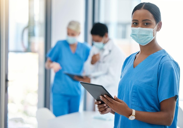 Foto médico de saúde ou enfermeiro em um tablet consultando em uma sala de reuniões de hospital trabalhadores médicos reunidos para consultar comunicação on-line gerenciamento de covid e médicos de trabalho em equipe usando máscaras cirúrgicas