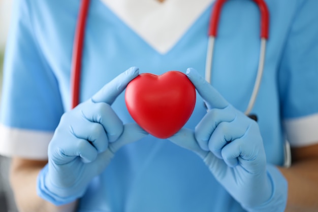 Médico de terno azul, luvas e com símbolo de espera de estetoscópio vermelho.