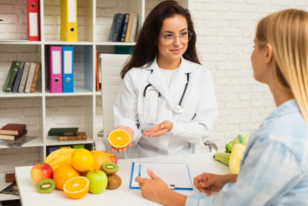 Médico de tiro médio falando com o paciente