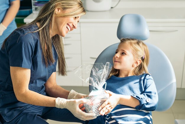 Médico dentista dando un regalo a una niña. Concepto medico