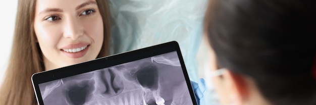 Foto médico dentista examina la radiografía de la mandíbula del paciente femenino