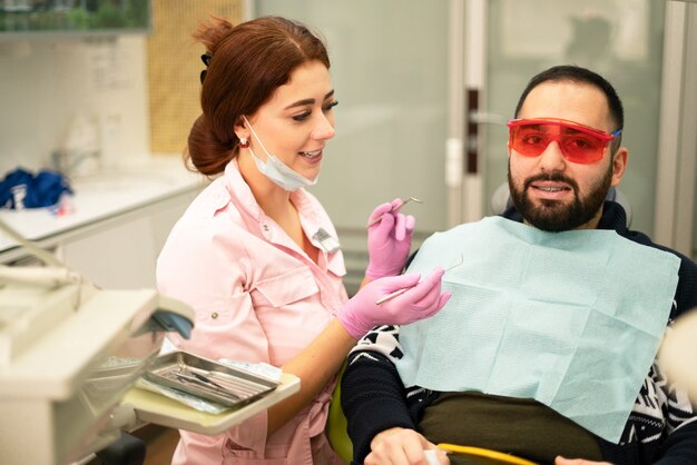 Médico dentista feminino jovem e paciente sorrindo para a câmera na clínica odontológica