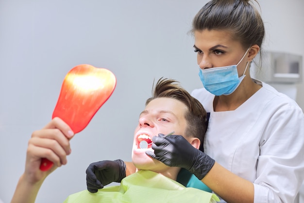 Médico dentista feminino trata os dentes para adolescente