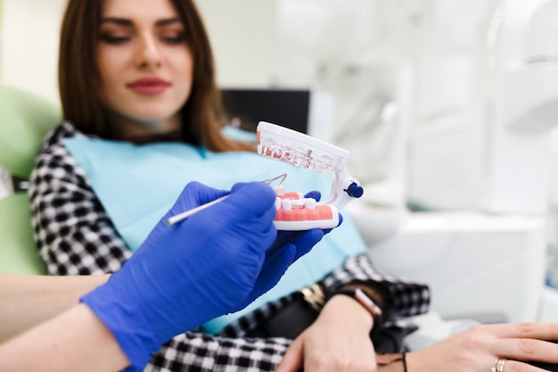 Médico dentista mostra ao paciente um modelo de mandíbula e fala sobre o próximo tratamento.