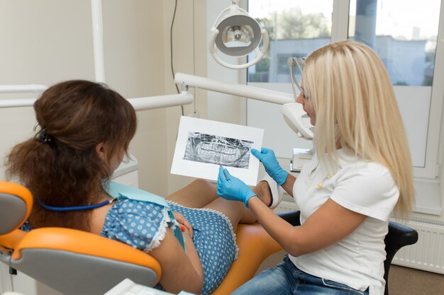 El médico dentista le muestra a un cliente una radiografía de los dientes