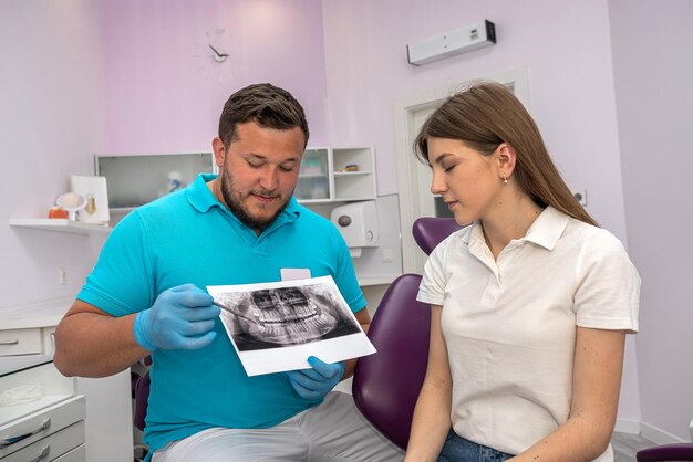 El médico dentista muestra una imagen de la mandíbula de un paciente joven