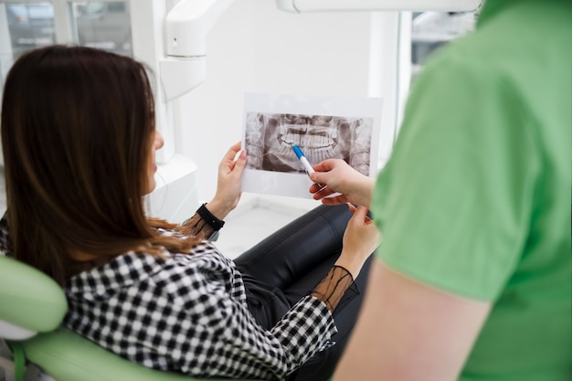 Médico dentista muestra una radiografía de la cavidad oral a su paciente