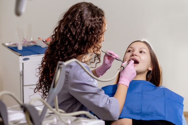 Médico dentista profissional examina e trata dentes estragados com o uso de instrumentos odontológicos especiais, equipamentos médicos