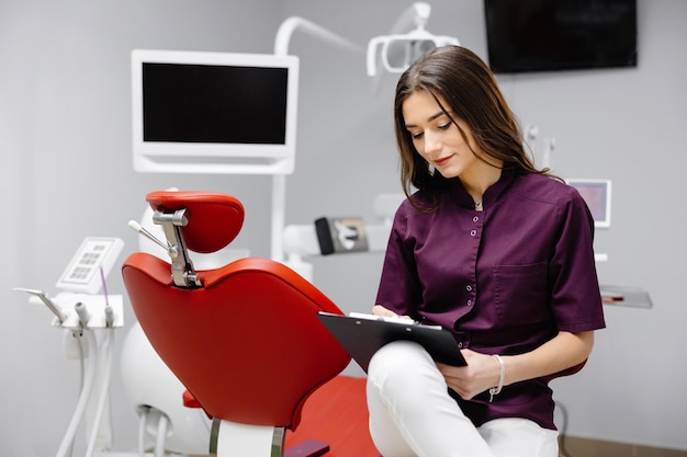 Médico dentista trabalhando no escritório usando a área de transferência e fazendo anotações