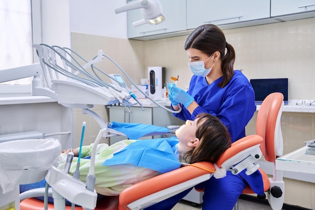 Médico dentista trata os dentes de uma jovem paciente adolescente