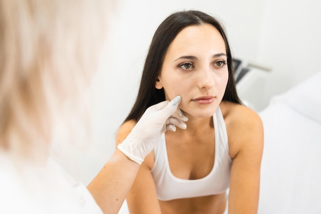 El médico dermatólogo examina los lunares en la piel de una mujer. Consulta antes de la depilación láser