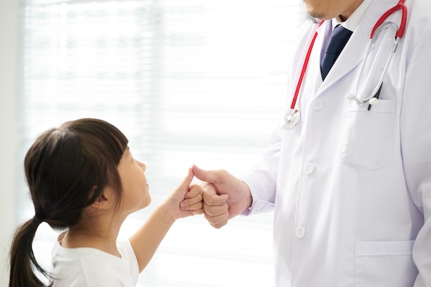 Médico desconhecido e garotinha apertando as mãos