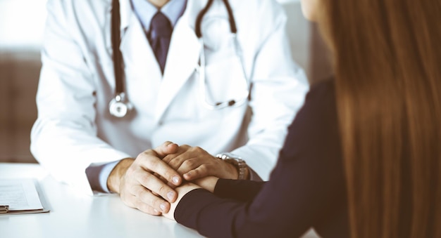 Médico desconhecido tranquilizando sua paciente, close-up. Dois médicos consultando e dando alguns conselhos à mulher. Serviço médico perfeito, empatia na medicina durante a pandemia de Coronavirus. Covid