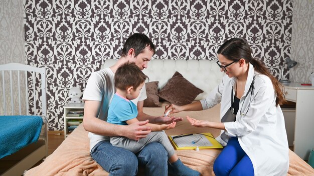 El médico desinfecta las manos del padre con el niño.