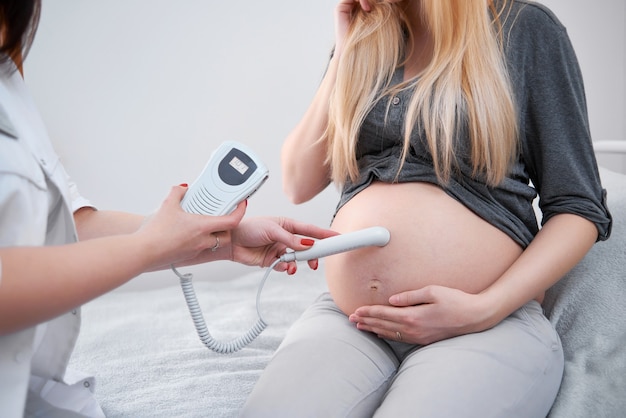 Médico diagnosticando mulher grávida e ouvindo batimentos cardíacos