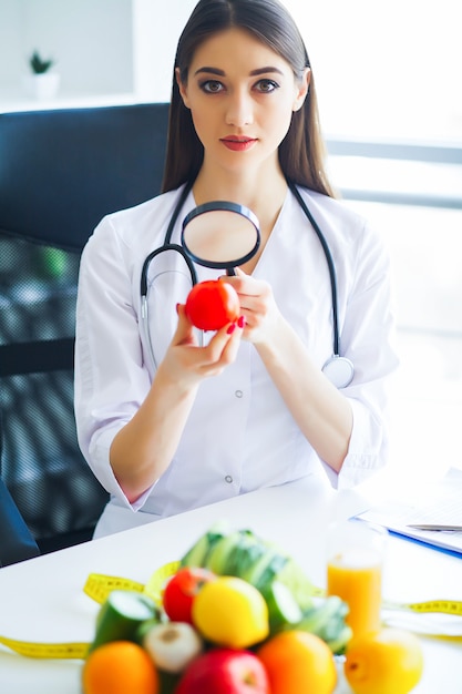 Médico dietista con tomates frescos en sus manos y sonrisas.