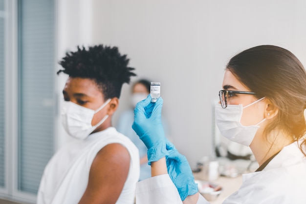 El médico le dio una inyección a un niño africano y se vacunó durante la pandemia de coronavirus o covid-19 en el hospital, concepto de vacunación