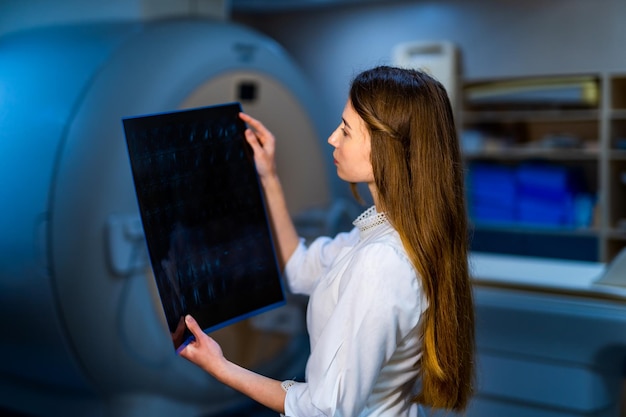 Foto médico do hospital segurando o filme de raio-x do paciente fundo moderno da máquina de ressonância magnética saúde roentgen pessoas e conceito de medicina