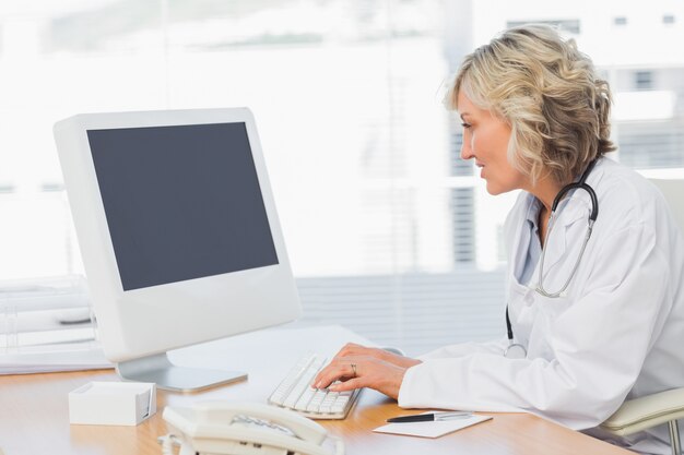 Médico do sexo feminino usando computador no consultório médico