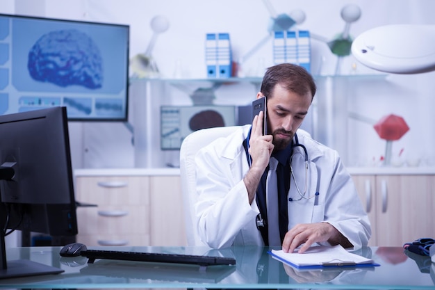 Médico do sexo masculino falando com um de seus pacientes do gabinete do hospital. Médico bonito de uniforme.