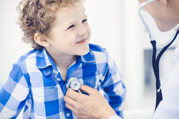 Médico e criança paciente. Médico examinando garotinho. Visita médica regular na clínica. Conceito de medicina e cuidados de saúde.