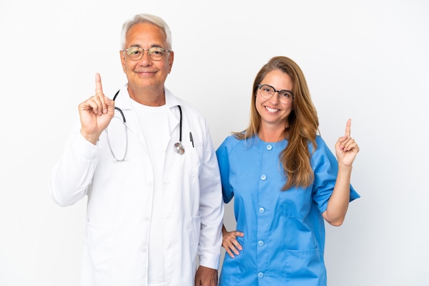 Médico e enfermeiro de meia-idade isolado no fundo branco mostrando e levantando um dedo em sinal dos melhores