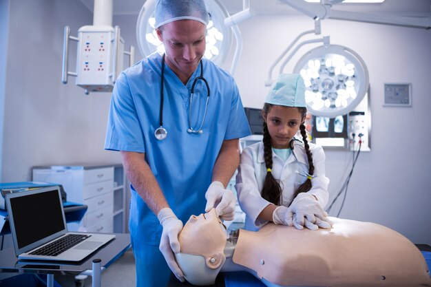 Médico e menina examinando um boneco