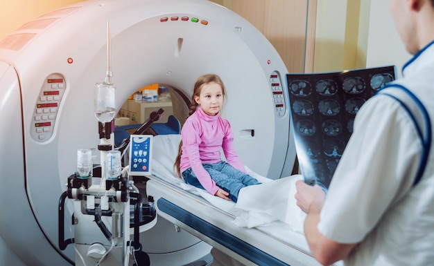 Médico e menina na sala de tomografia computadorizada