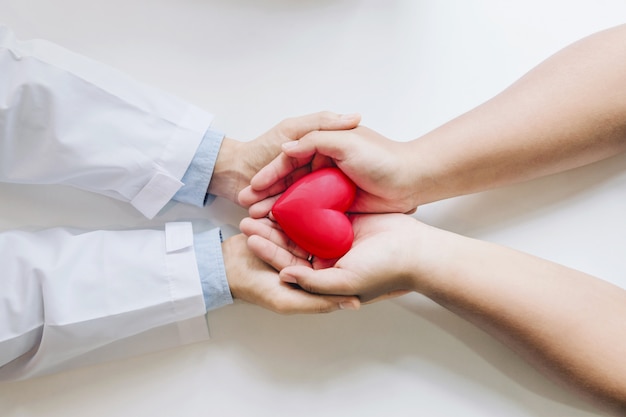 Foto médico e o paciente segurando um coração vermelho juntos.
