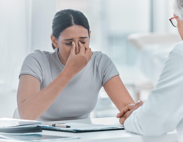 Médico e paciente com estresse de dar as mãos no consultório com feedback sobre o diagnóstico Pessoas profissionais médicos e mulher triste na clínica para más notícias sobre a doença com apoio e cuidados