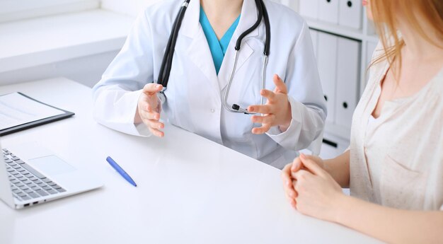 Médico e paciente discutindo algo enquanto está sentado na mesa do hospital, close-up. Medicina e cuidados de saúde