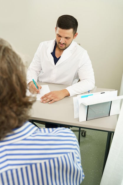 Médico e paciente do sexo masculino de meia idade durante a consulta