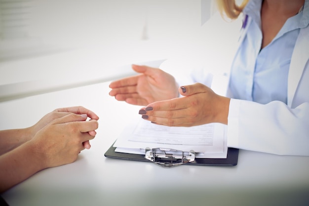 Médico e paciente estão discutindo algo apenas com as mãos na mesa