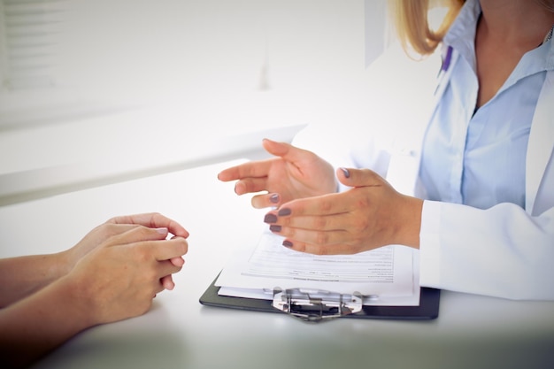 Médico e paciente estão discutindo algo, apenas mãos na mesa.