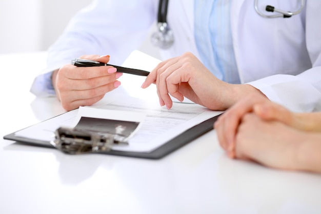 Médico e paciente estão discutindo algo, apenas mãos na mesa.