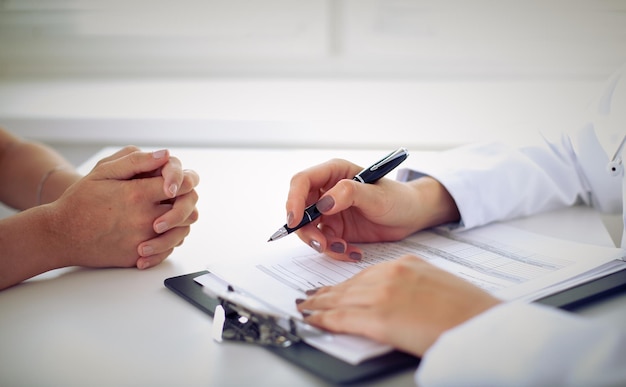 Médico e paciente estão discutindo algo, apenas mãos na mesa.