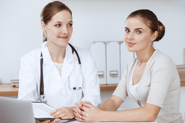 Médico e paciente estão sentados e discutindo os resultados dos exames de saúde no consultório da clínica. Conceitos de cuidados de saúde, medicina e boas notícias.